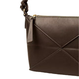 A close-up view of a brown leather handbag with a zipper closure and a small handle.