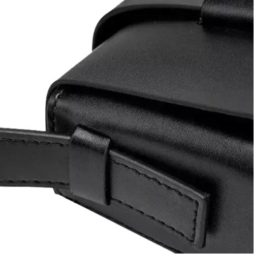 A close-up view of a black leather handbag or briefcase, showing its details such as the strap, zipper, and pocket.