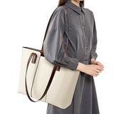 A woman wearing a gray dress and carrying a large white tote bag.