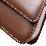 A close-up view of a brown leather handbag, showcasing its detailed stitching and texture.