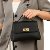A person wearing a gray blazer and holding a black leather handbag with a gold lock.