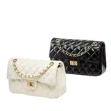 two handbags, one white and one black, with gold chain straps and buckles.