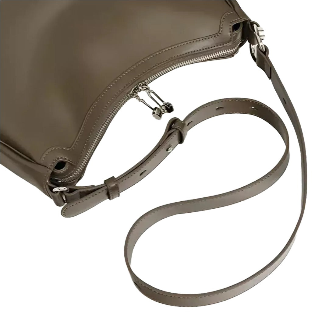 A close-up view of a brown leather handbag with a curved strap and zipper closure.