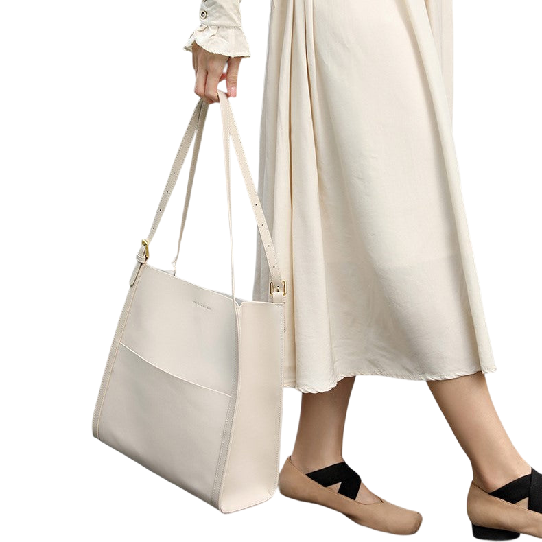 A woman wearing a long white dress and carrying a white tote bag is walking.