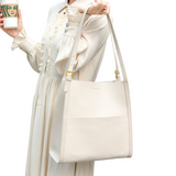 A woman in a white dress holds a white handbag and a cup of coffee.