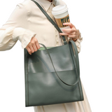 A person is holding a green handbag and a coffee cup, with their hand visible as they hold the cup.