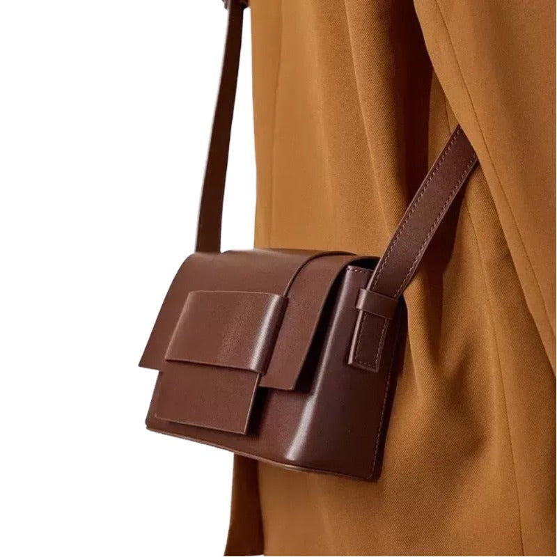 A brown leather handbag with a structured design and a strap.