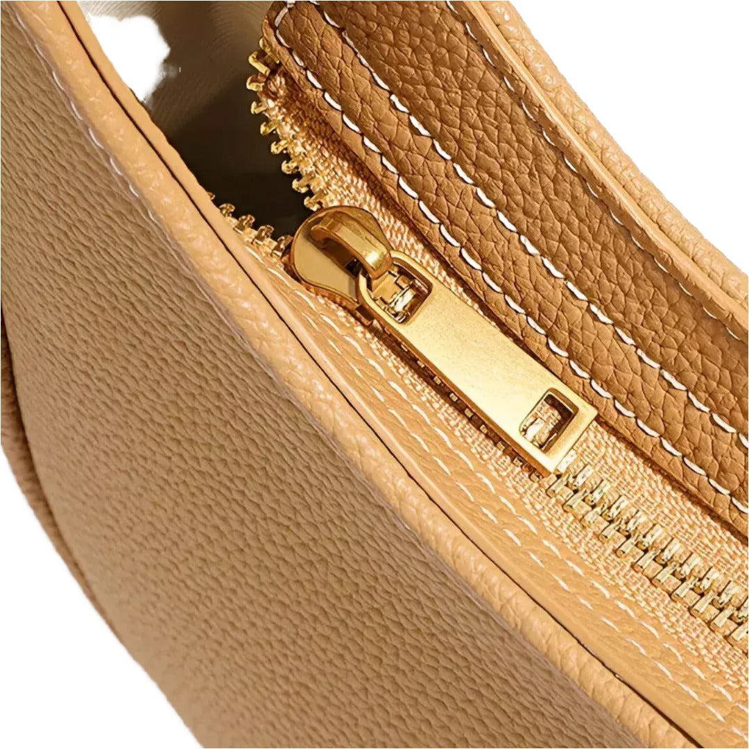 A close-up view of a tan leather handbag zipper with a gold zipper pull.