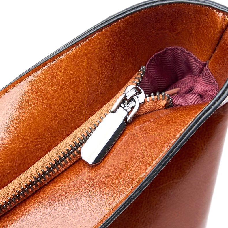 A close-up view of a brown leather purse with a zipper and a small compartment inside.