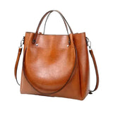 A brown leather tote bag with a shoulder strap and two handles, displayed against a white background.