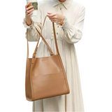 A woman in a white dress holding a tan leather handbag and a cup of coffee.