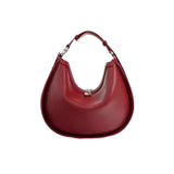 A red leather handbag with a curved shape and a metal clasp on the front.