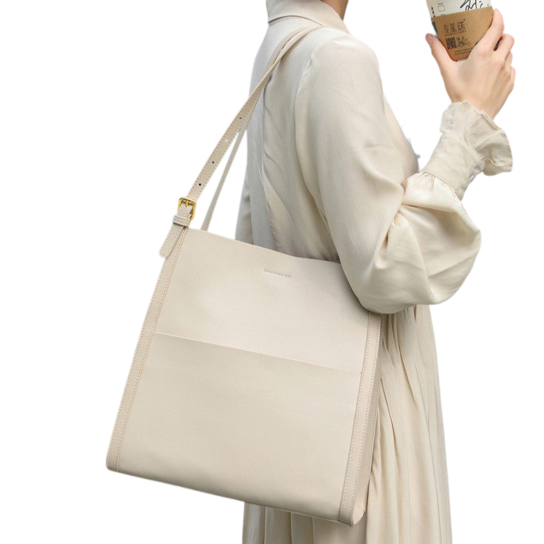 A person wearing a white dress and carrying a beige handbag is holding a coffee cup in their hand.