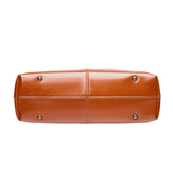 A brown leather tote bag with a curved top and two metal studs on the bottom.